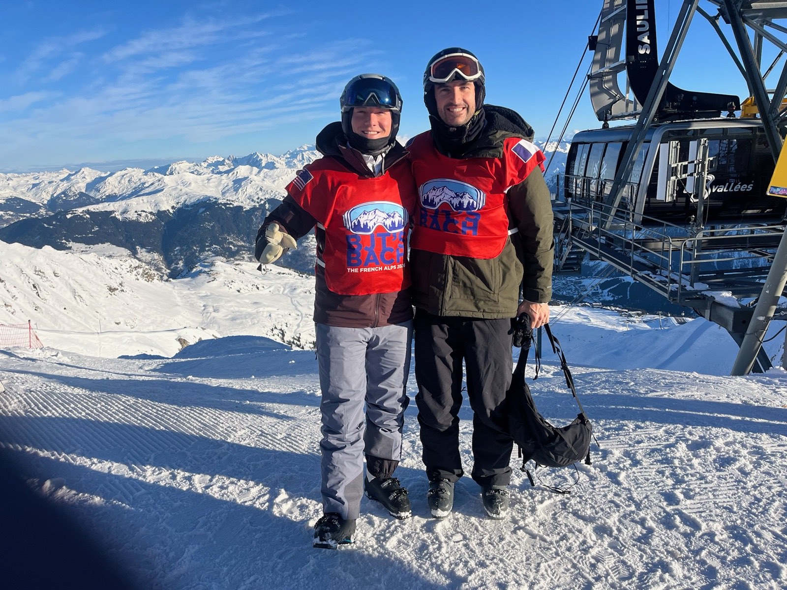 Two skiers in matching red sublimated group bibs above the Three Valleys